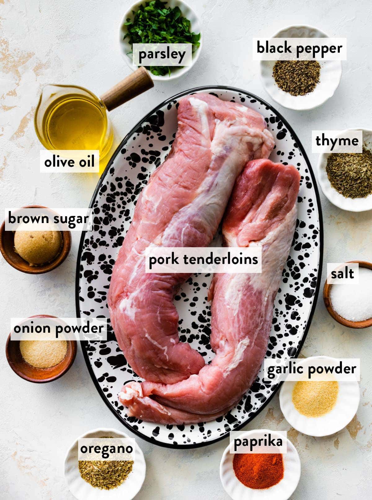 pork tenderloins on a tray surrounded by small bowls of seasonings.