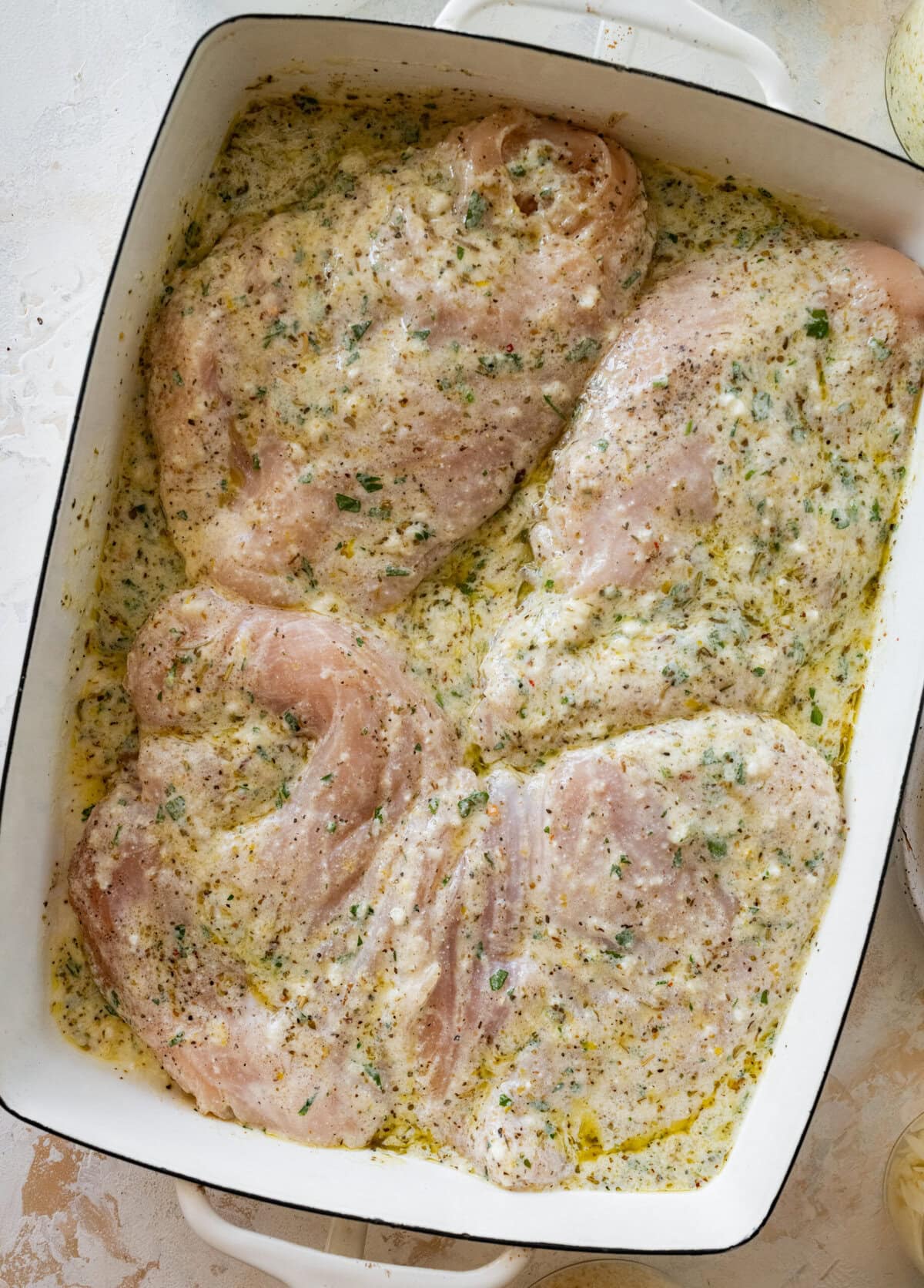 chicken breasts in a pan with the marinade on top.