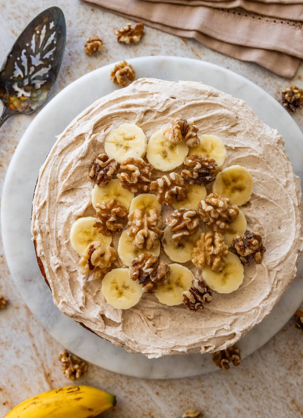 Frosted banana nut cake garnished with nuts and banana slices.