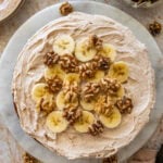 Frosted banana nut cake garnished with nuts and banana slices.