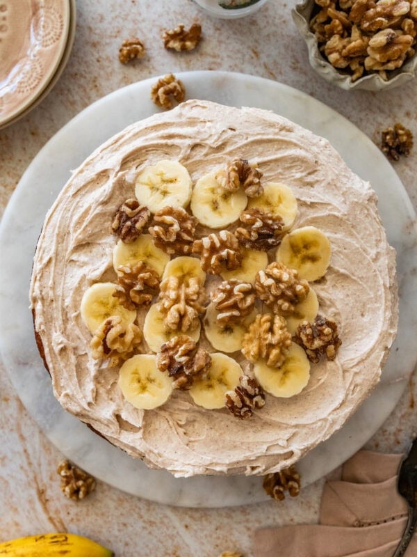 Frosted banana nut cake garnished with nuts and banana slices.