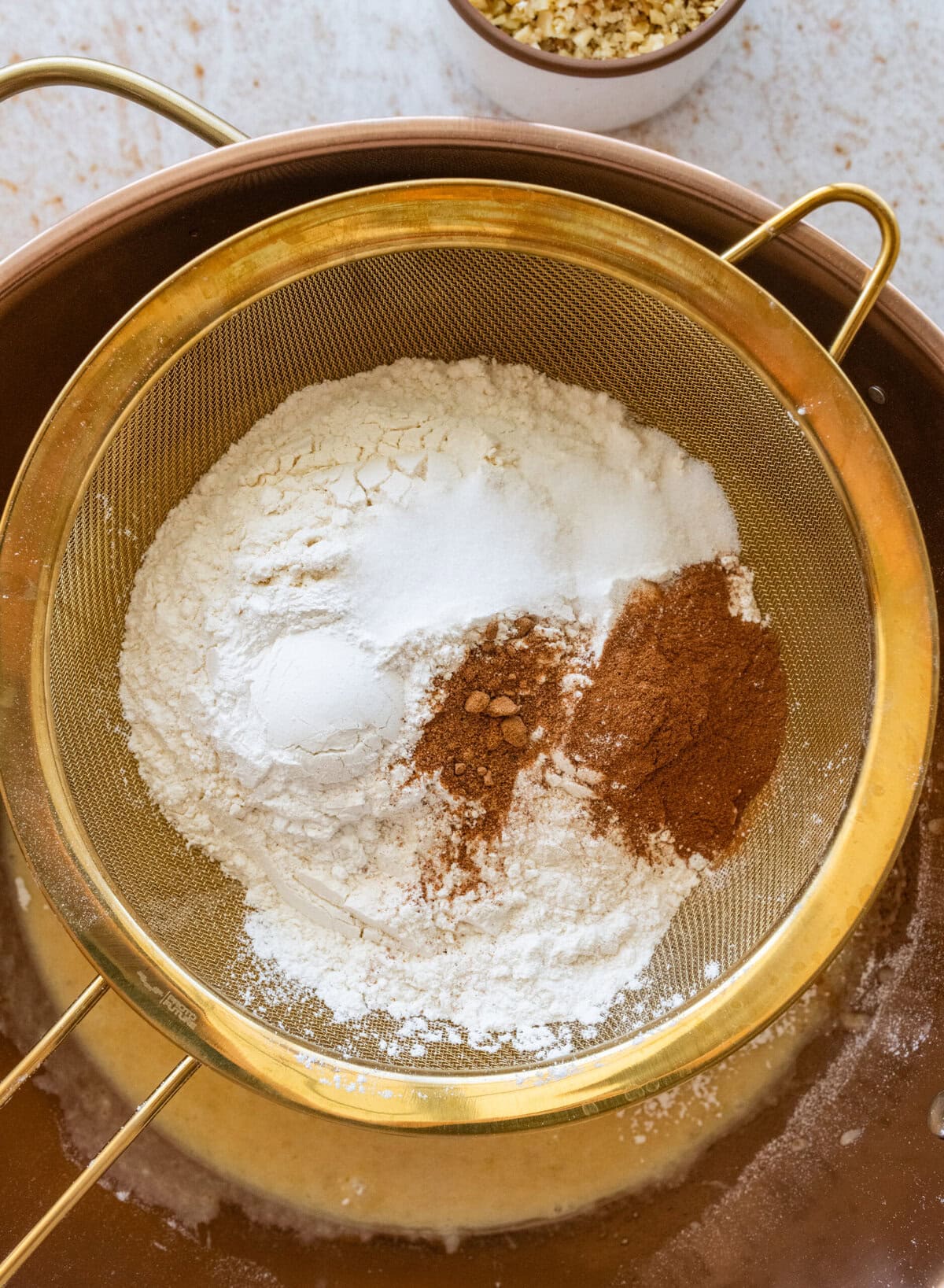 The dry ingredients for the batter being sieved into the bowl of wet ingredients.