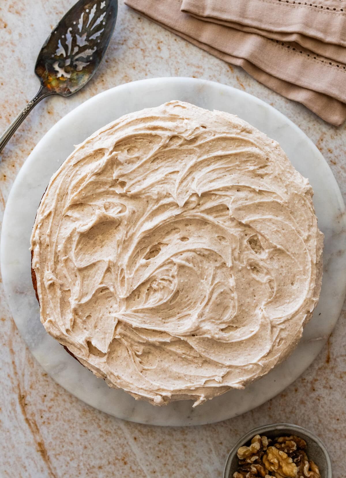 Banana nut cake on a large dish after iced with frosting.