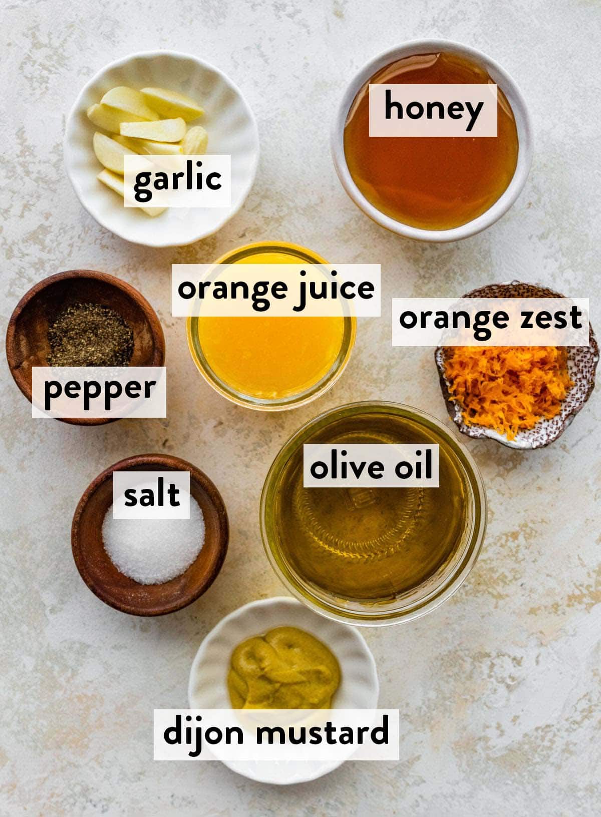 bowls of ingredients for orange vinaigrette on a countertop.