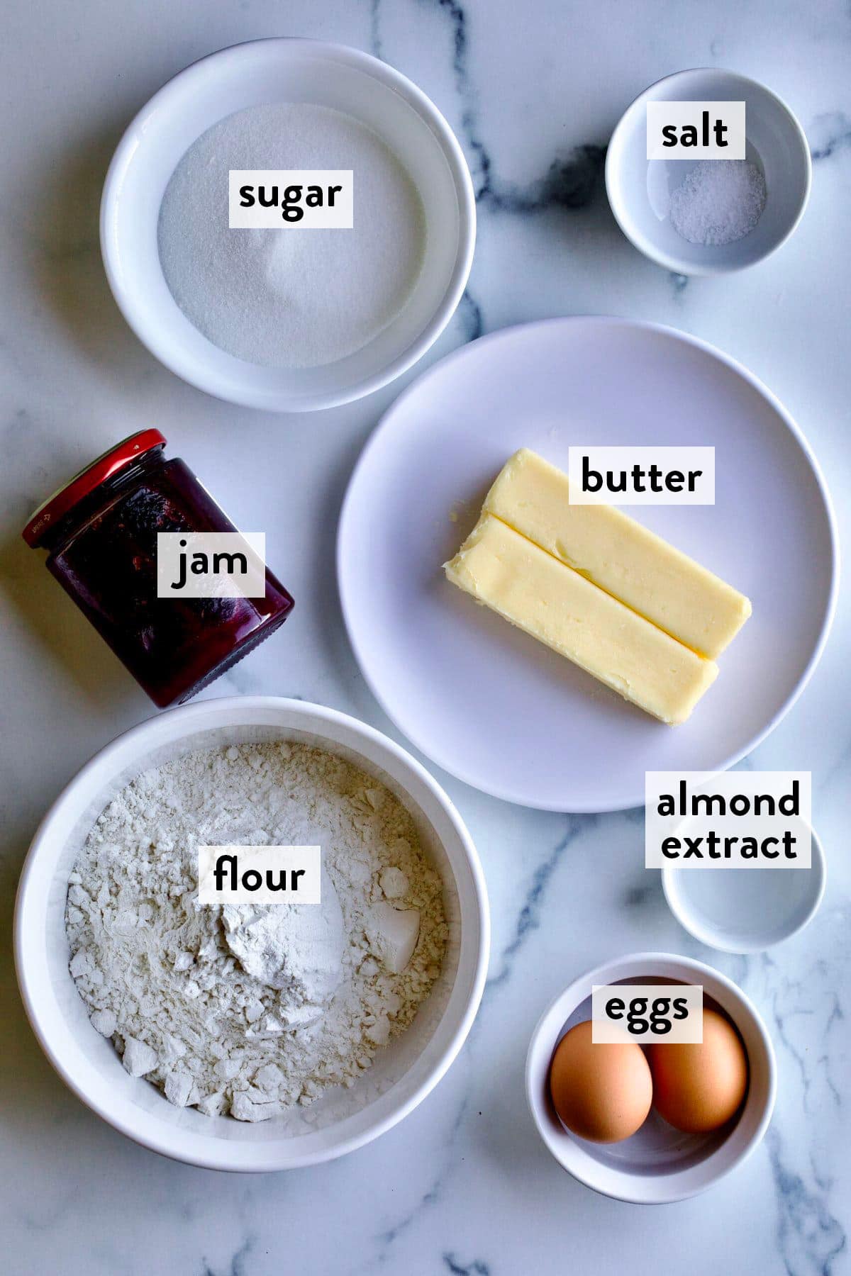 bowls of ingredients for thumbprint cookies on a marble countertop.