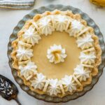 banana cream pie topped with sliced bananas and piped whipped cream.