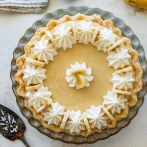 banana cream pie topped with sliced bananas and piped whipped cream.
