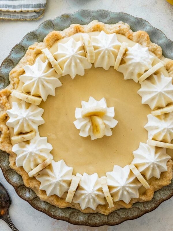 banana cream pie topped with sliced bananas and piped whipped cream.