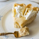 slice of banana cream pie with a forkful of pie on a small plate.
