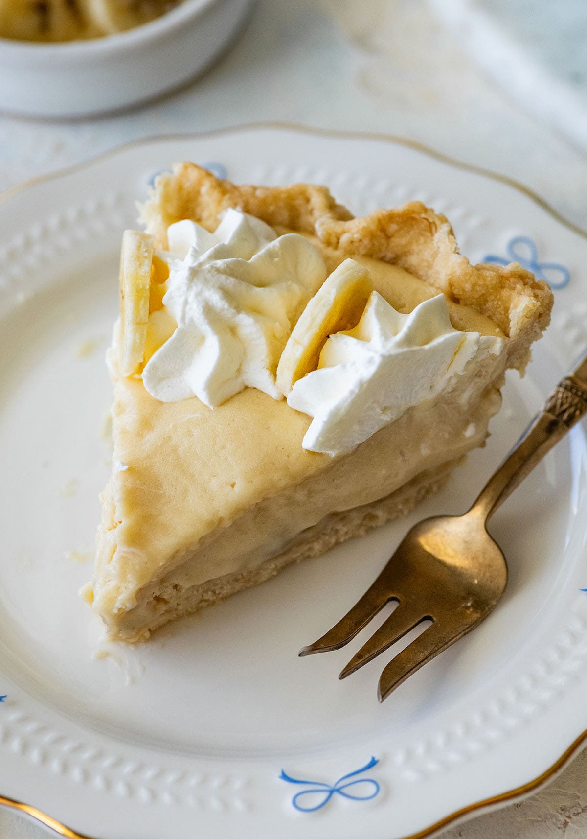slice of banana cream pie on a small plate with a fork.