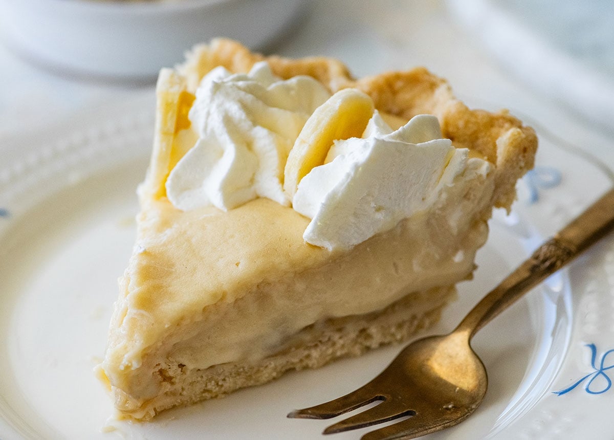 slice of banana cream pie on a small plate with a fork.