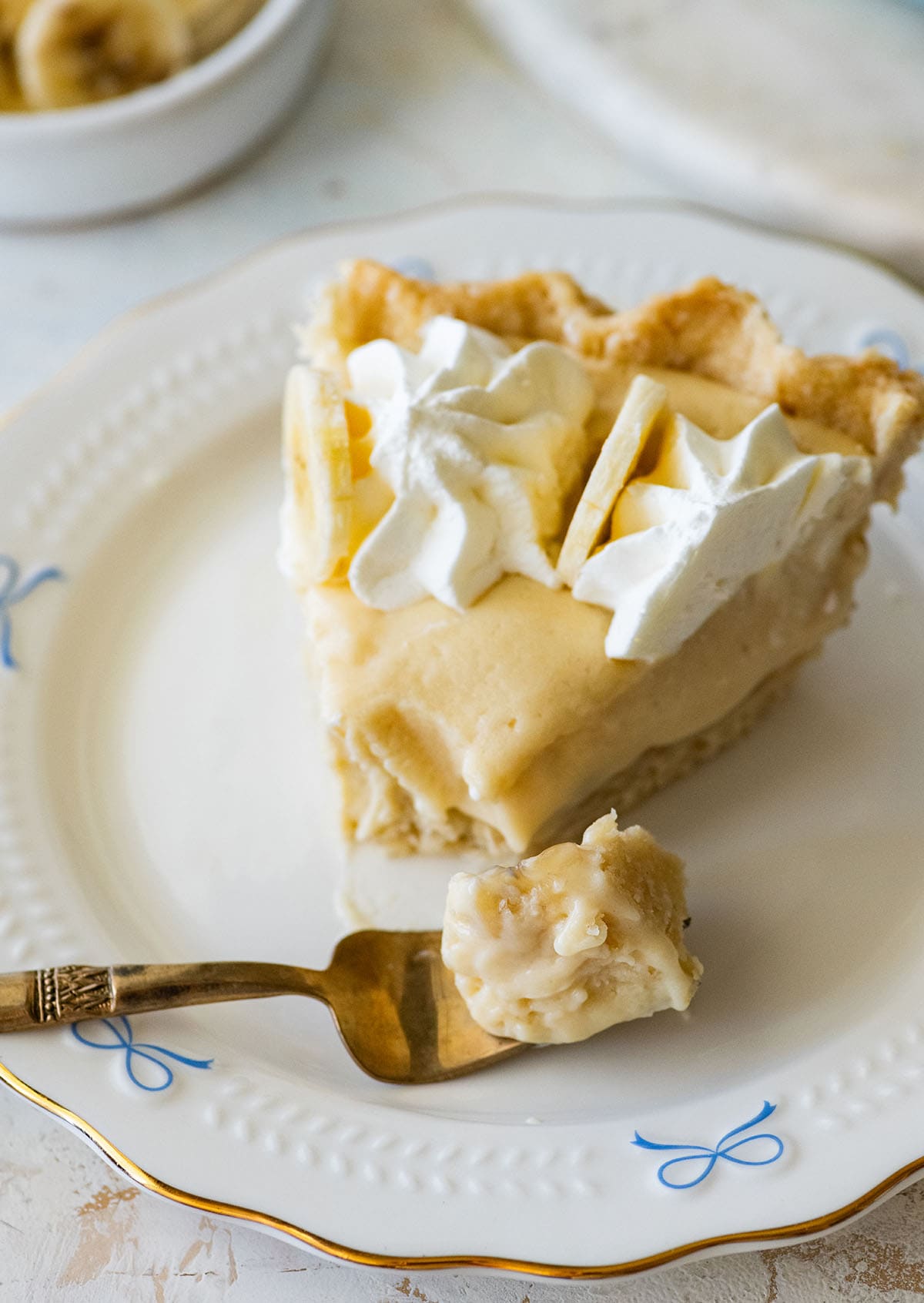 slice of banana cream pie with a forkful of pie on a small plate.