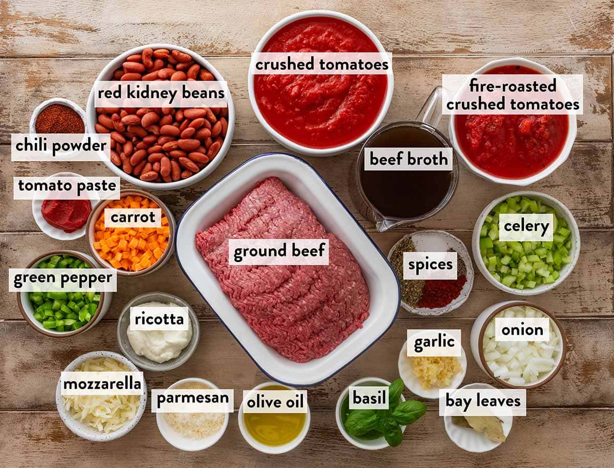 bowls of ingredients for beef and bean chili on a wooden table.