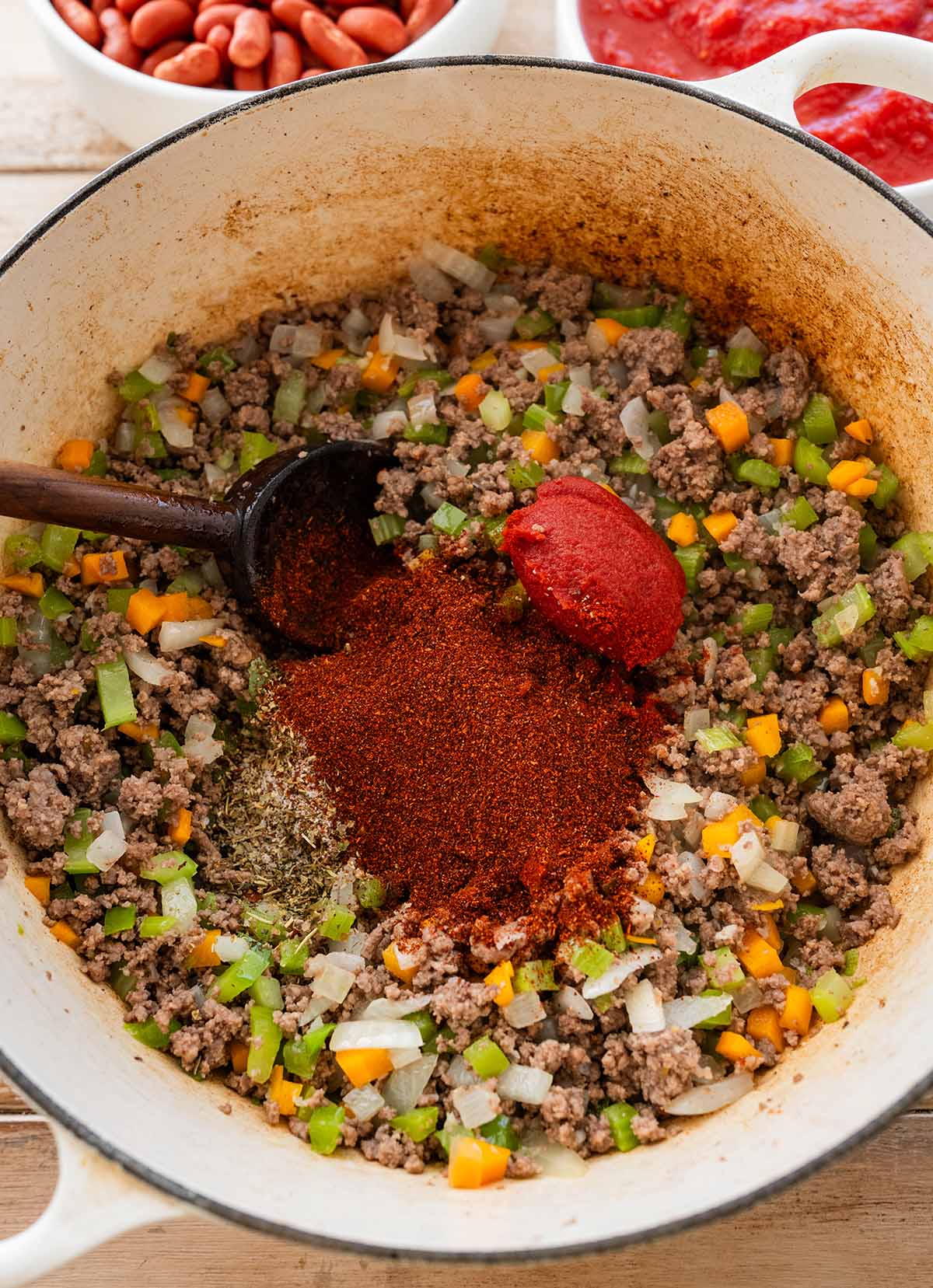 adding seasonings and tomato paste to the ground beef and sofritto mixture.