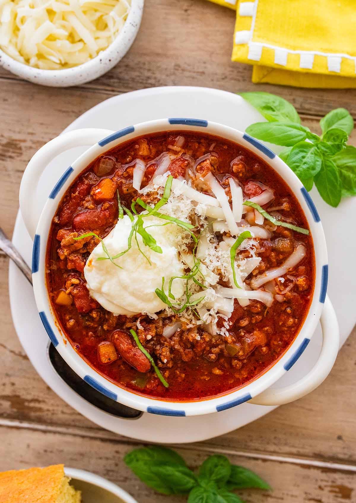 bowl of beef and bean chili topped with cheese and basil ribbons.