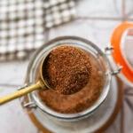 A scoop of seasoning held over a jar with more.