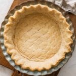 baked Crisco pie crust in a ceramic pie crust on a wooden cutting board.