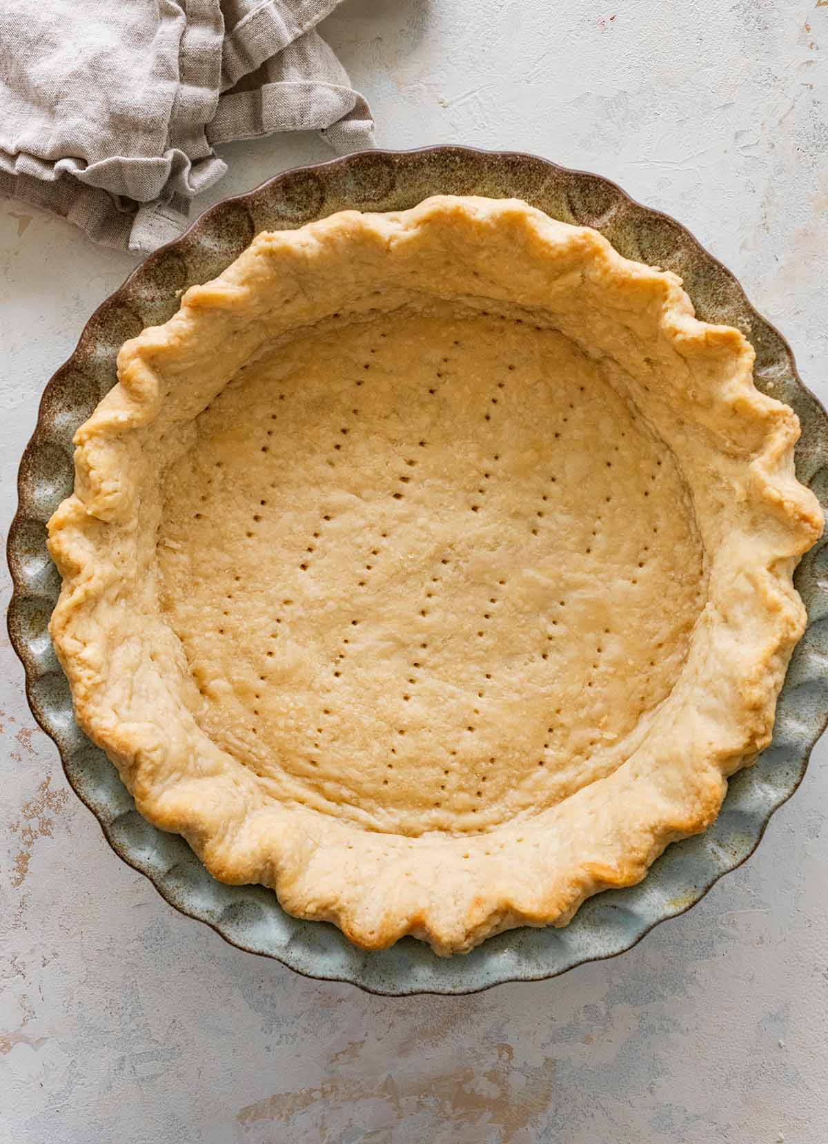 baked Crisco pie crust in a ceramic pie dish with a napkin.