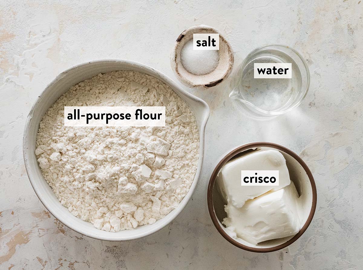 bowls of ingredients for Crisco pie crust on a marble countertop.