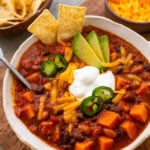 A bowl chili with toppings on top and a spoon resting inside.