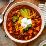 A bowl chili with toppings on top.