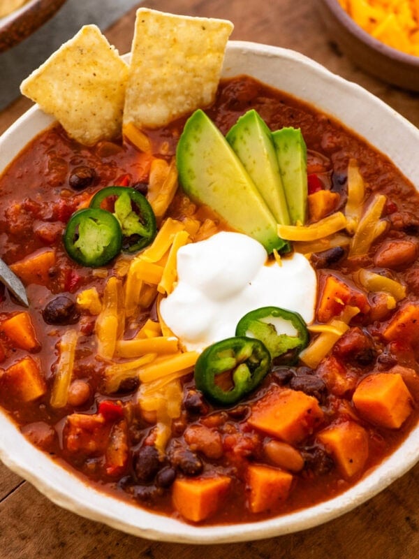 A bowl chili with toppings on top and a spoon resting inside.