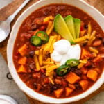 A bowl chili with toppings on top.